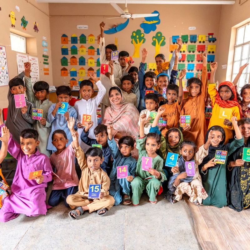Students with their teacher, Shazia, at a foundational literacy and numeracy camp at Government Model Primary School, Lashkar, Bahawalpur.